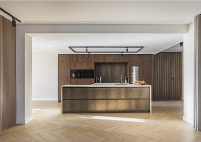 Moderne keuken met bronzen kookeiland, houten wandpanelen en visgraat vloer